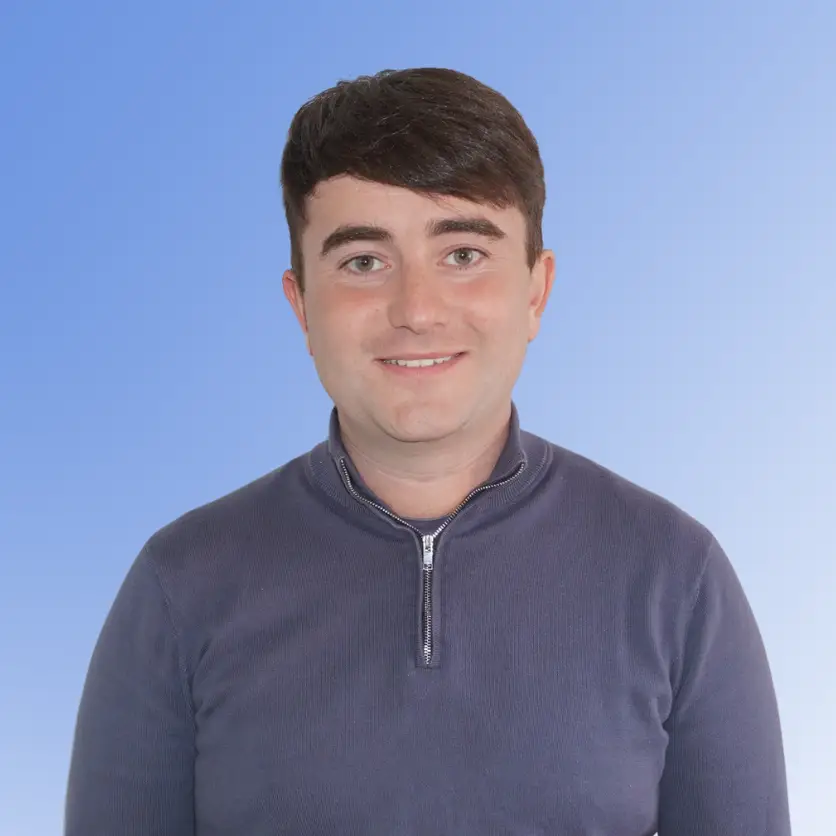 Dan Brennan, Senior Consultant at ACE Partners, smiling in a dark quarter-zip sweater against a blue background.