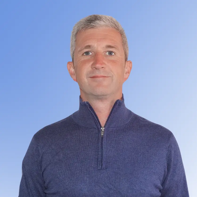 Danny McLaughlin, Senior Consultant at ACE Partners, wearing a blue quarter-zip sweater against a light blue background.